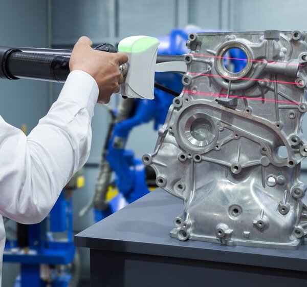 Image showing an engineer working with a portable measuring instrument.To the right of the image an aluminium automotive part sits on a bench being scanned by an engineer with a portable measuring instrument.
