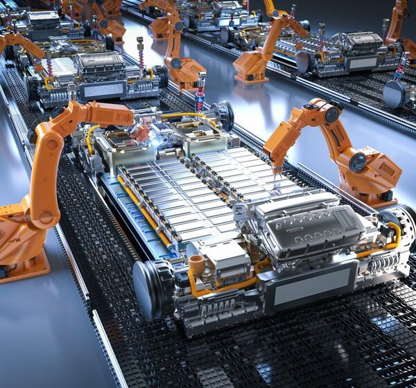 Image showing an electric car battery assembly line. In a sterile room a row of orange robotic arms are manufacturing electric car batteries on an assembly line.