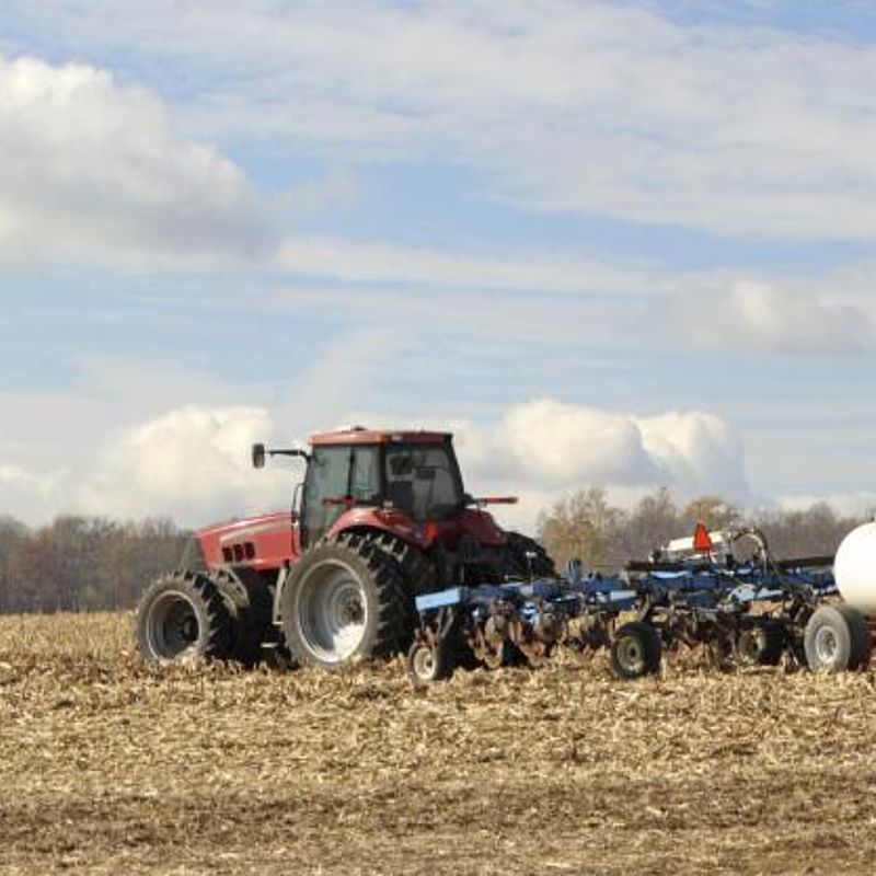 Image showing a tractor plowing and fertilising a field