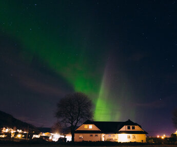 Image showing Northern Lights in the wintertime above a village in Scandinavia