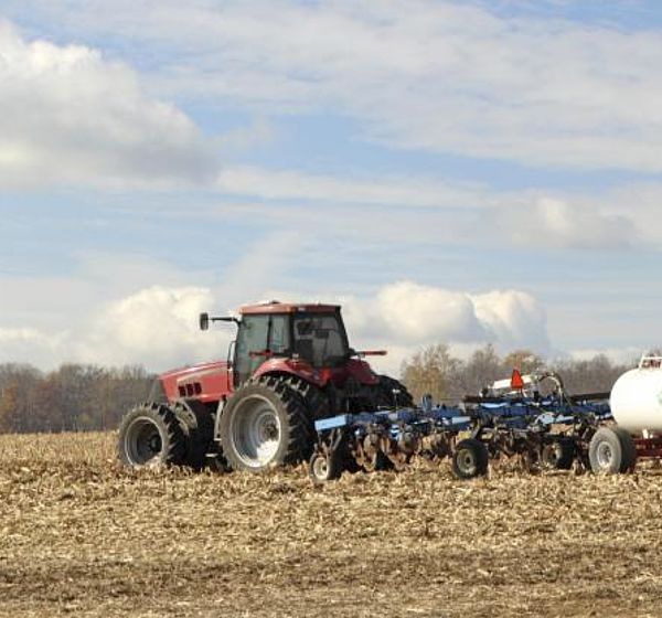 Image showing a tractor plowing and fertilising a field