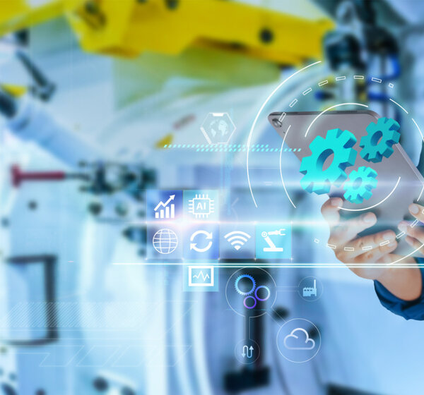 Man hands pointing at virtual blue gears on blurred robot arm and factory as background