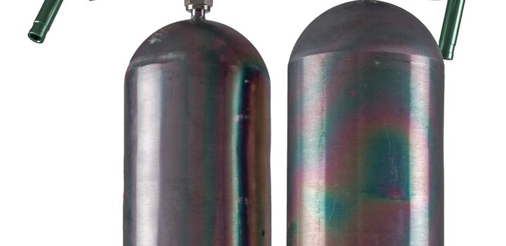 Two cylinders filled with primary reference gas mixtures for halogenated VOCs in front of a white background