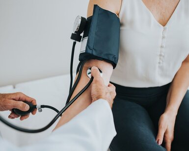 Image showing a doctor taking a patient’s blood pressure Alt description: Close up of a patient wearing a blood pressure cuff with a doctor taking the blood pressure. 