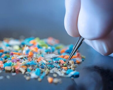 Image showing a person with medical gloves and tweezers inspecting a pile of microplastics