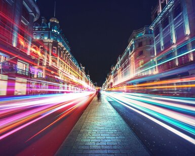 Image showing a timelapse image of lights streaming past a pedestrian
