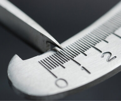 Close up image of a steel measurement calliper with the needle between 0.5 and 1.0 to demonstrate that every measurement contains an element of uncertainty