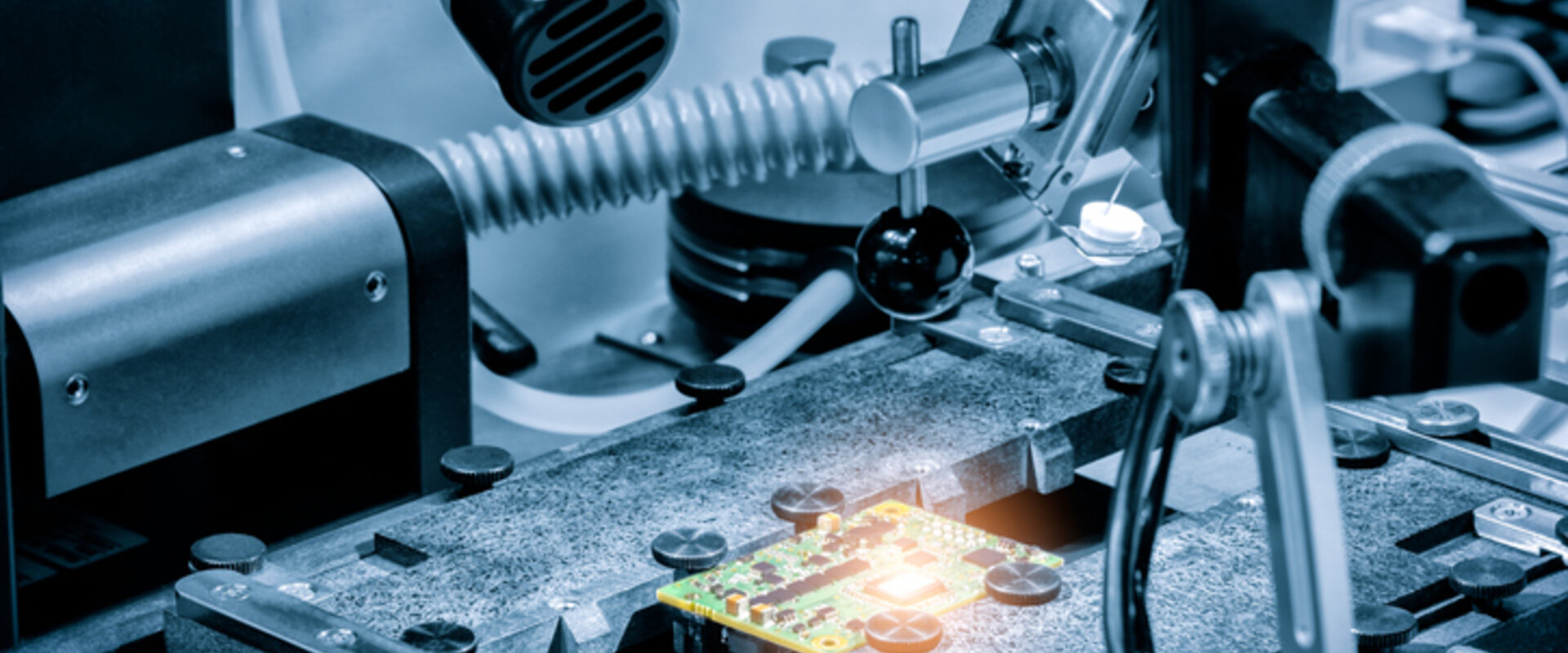A grey and silver image of a silicon chip surrounded by various testing equipment