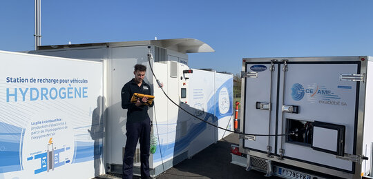 A technician monitors the Cesame-Exadebit mobile secondary measurement standard on a tablet computer while calibrating a hydrogen refuelling station
