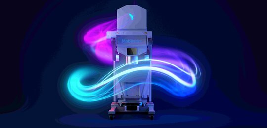 Against a dark background is the Mobetron clinical linear accelerator. A tall, white, box-like instrument on wheels surrounded in the picture with glowing lines