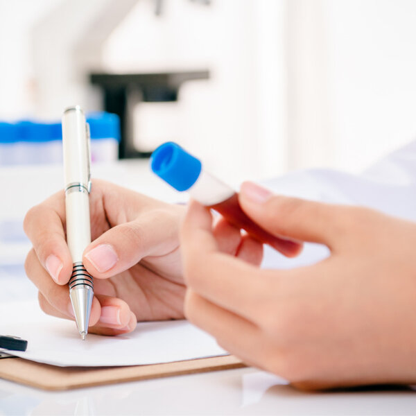 Image of a scientist recording blood anaysis results in laboratory