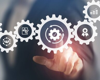 Image showing a person in a business suit pointing to a graphic showing interconnected cogs which each contain an icon of a different industry concept