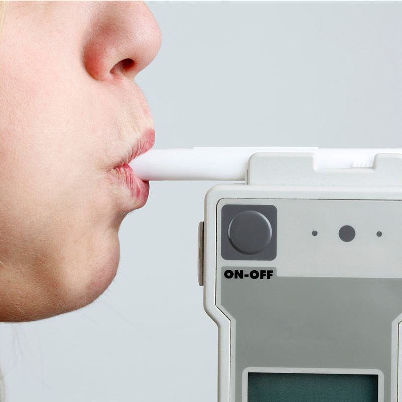 Ensuring the accuracy of breath analysers to enforce drink driving regulations Image showing a person blowing in breathalyser