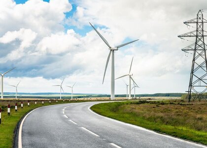 Wind turbines and high voltage power lines on either side of a country road