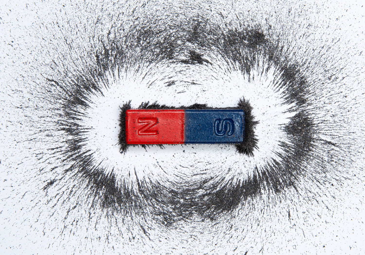 Image of a bar magnet with iron powder showing magnetic field