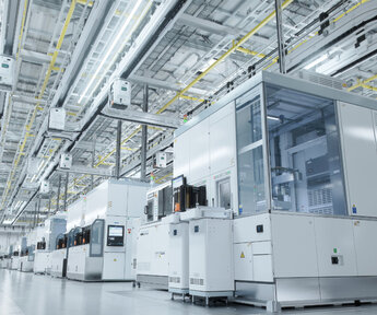 In a brightly lit and sterile semiconductor clean room rows of production booths spread out into the distance