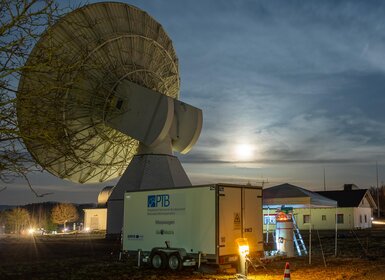 Image showing the measurement trailer and the TeleYAG-II interferometer mounted on a surveying pillar in front of a radio telescope and two satellite-laser-ranging domes at the Geodetic Observatory Wettzell, Germany