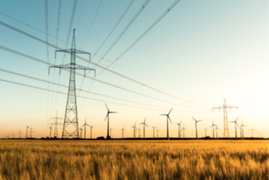 Image showing a large electricity pylon with wind turbines in autumn setting