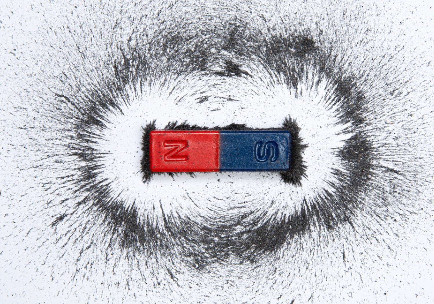 Image of a bar magnet with iron powder showing magnetic field